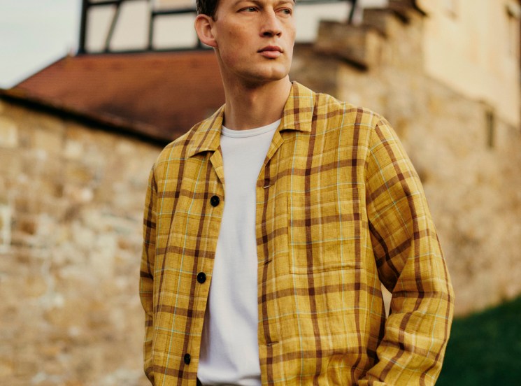 Model wearing yellow plaid Paul Smith jacket with white t-shirt and beige trousers