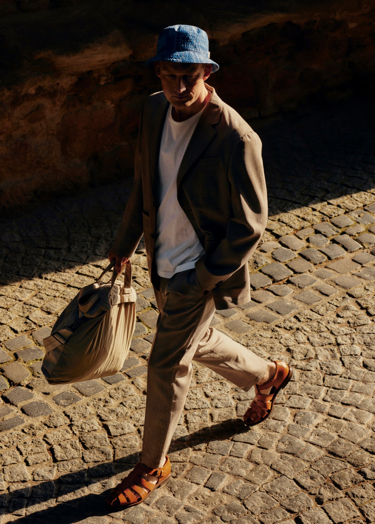 Model in casual jacket and trousers with hat and bag accessories