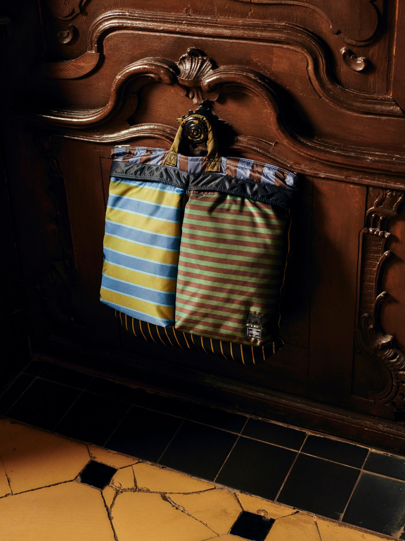 Close-up of colourful striped bag by Paul Smith x Porter hanging on ornate wooden furniture