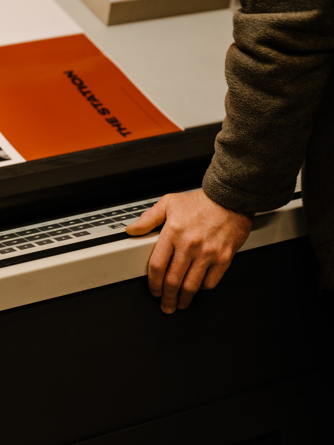 Hand resting on laptop keyboard next to orange book displaying 'The Steidl Book' text
