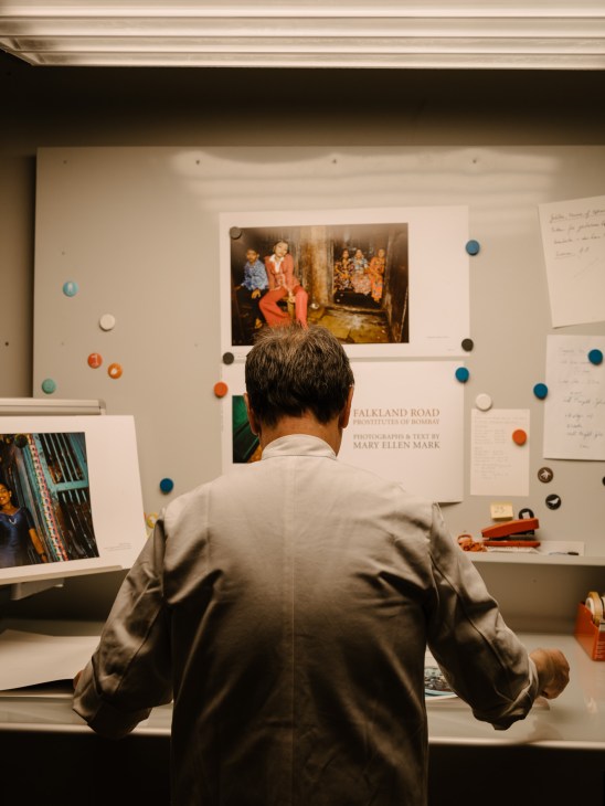 Gerhard Steidl in his white apron examining printed materials at his printing press facility