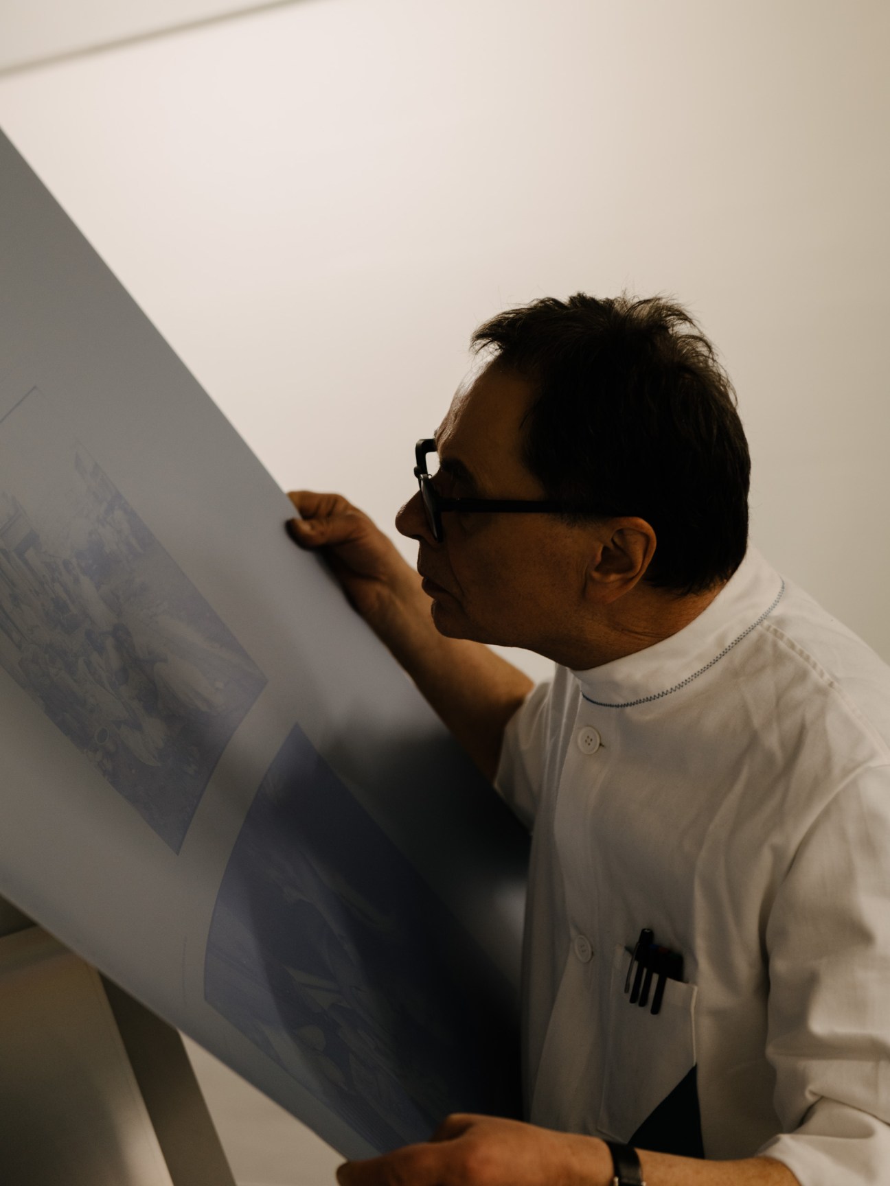 Gerhard Steidl examining a printing plate with careful attention to detail in his workshop