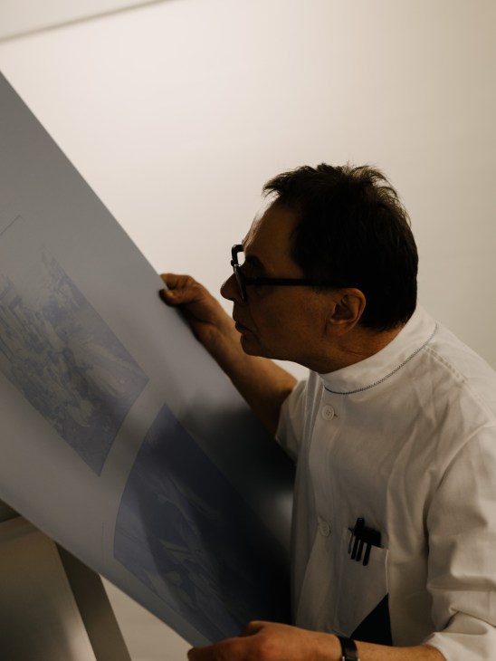 Gerhard Steidl examining a printing plate with careful attention to detail in his workshop
