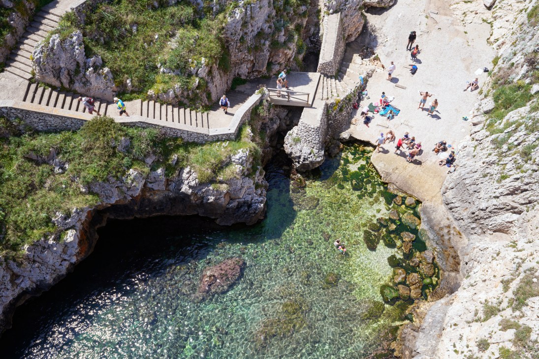 Dramatic rocky coastline with clear turquoise water and limestone cliffs at Porto Ciolo Beach