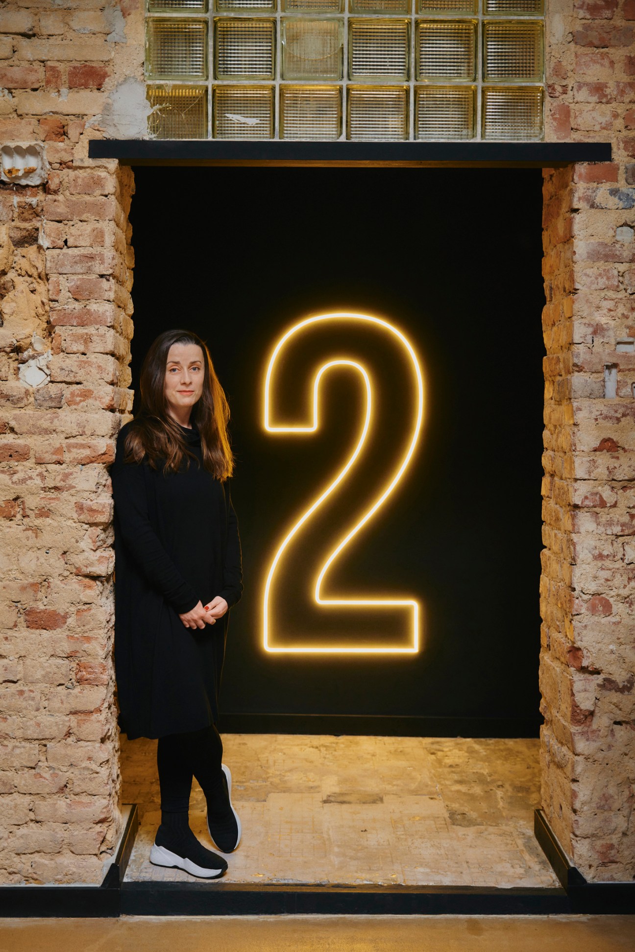 Production manager Denisa Hadj Moussa stands before a neon number 2 sign at Kabelovna Studios in Prague.