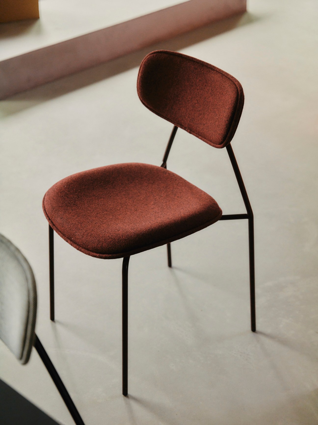 Master & Master's stackable Mistra chair with rust-colored fabric and black metal frame.