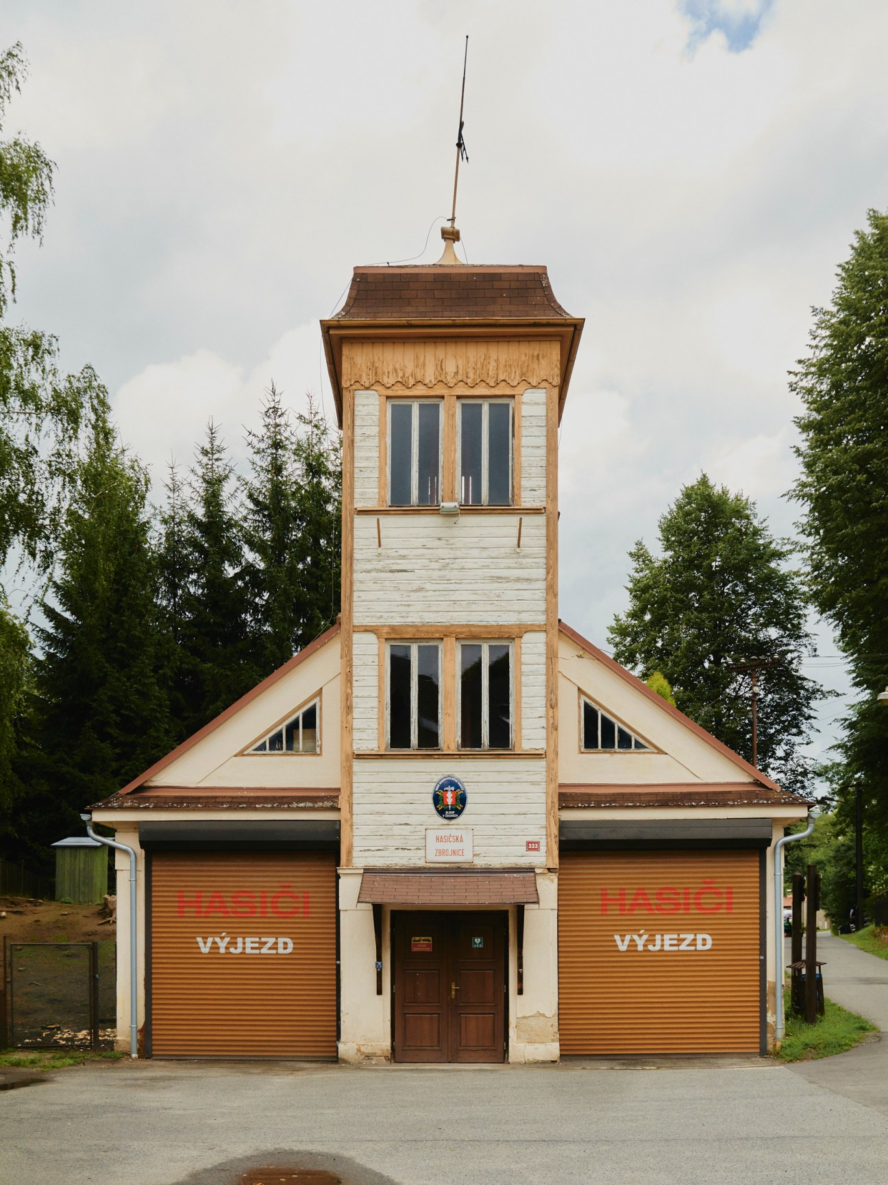 White wooden fire station with observation tower, showing Czech text 'HASICI VYJEZD' on brown garage doors