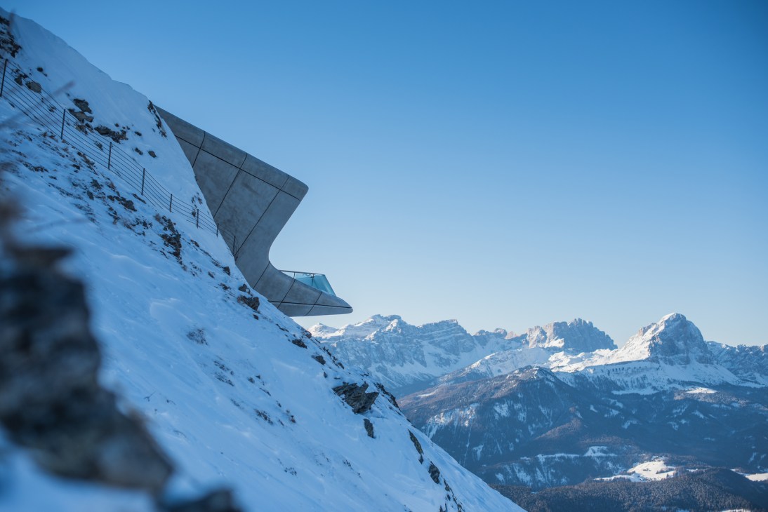 Zaha Hadid-designed Messner Mountain Museum with angular concrete structure built into snowy Dolomites mountainside.