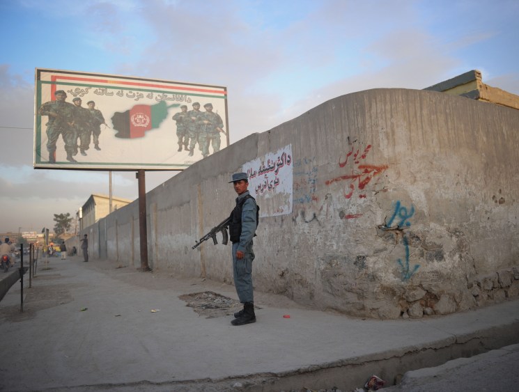 ANA soldier in Kandahar stands in front of an army recruitment poster