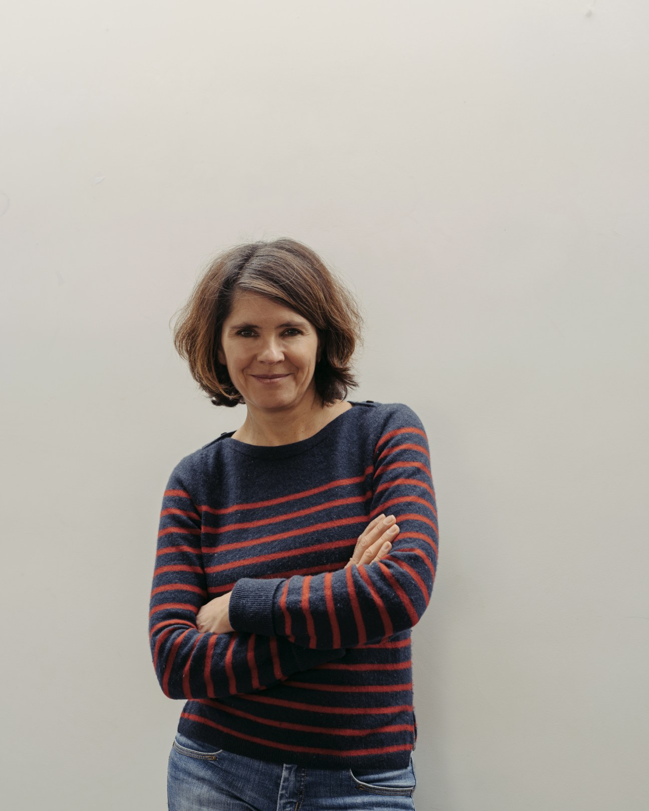 Emmanuelle Aubry, the newspaper's deputy editor, wearing a striped sweater with arms crossed