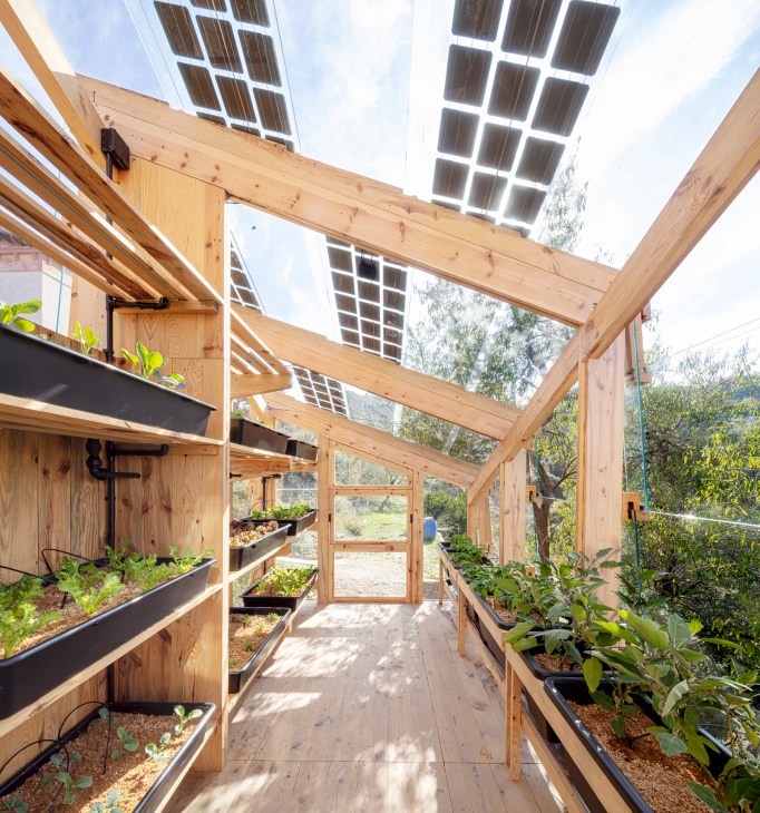 Solar Greenhouse by IAAC students featuring wooden timber frame construction with solar panels and hydroponic growing systems