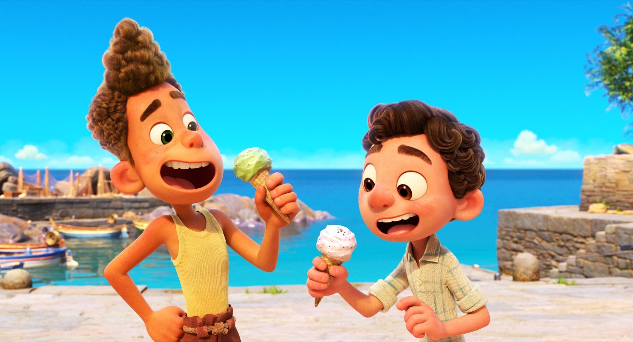 Two animated young boys holding ice cream cones on a beach overlooking the Italian Riviera in Pixar's Luca.