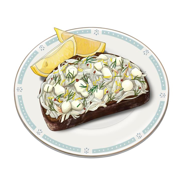 Crab toast topped with white crab meat, herbs and lemon wedges on a decorative plate