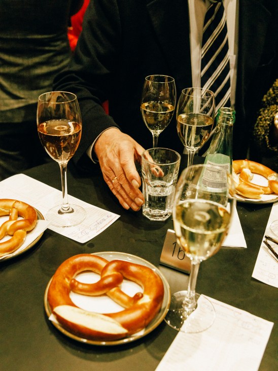Opera patrons enjoying champagne and traditional German pretzels during intermission