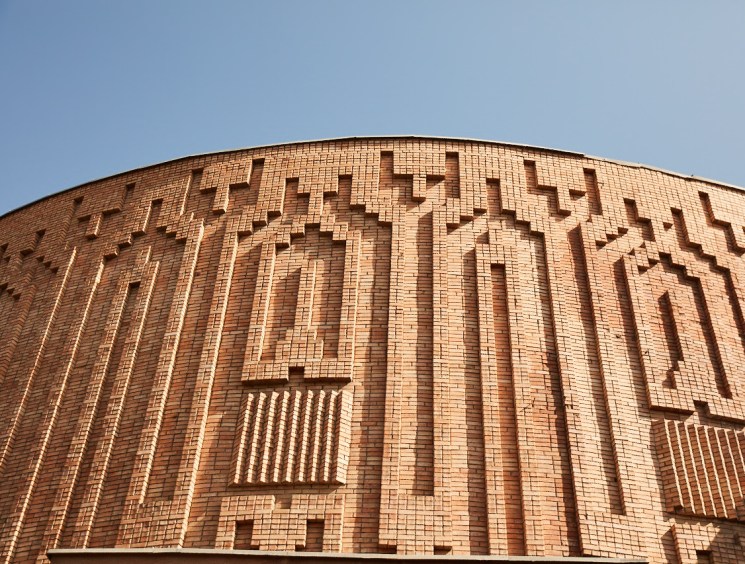 Curved brick building facade with intricate geometric relief patterns.