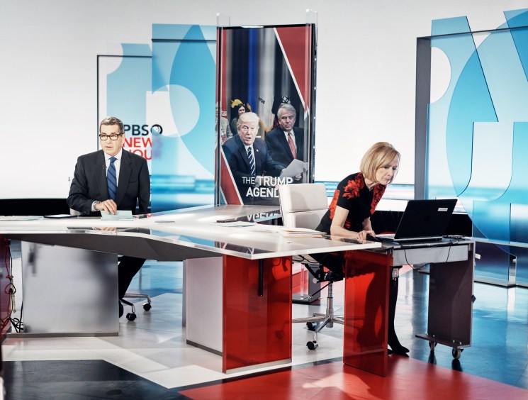 PBS Newshour anchors Miles O'Brien and Judy Woodruff at desks in the studio during a pre-recorded segment.