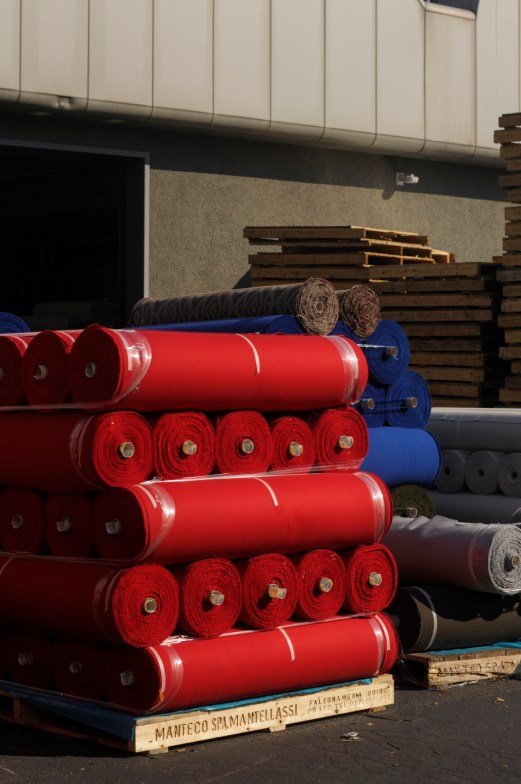 Stacked rolls of red, blue and other colored recycled wool fabric in warehouse with wooden pallets