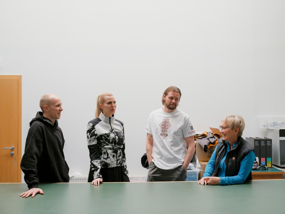 Four 66°North employees having a casual discussion around a green conference table in a modern office