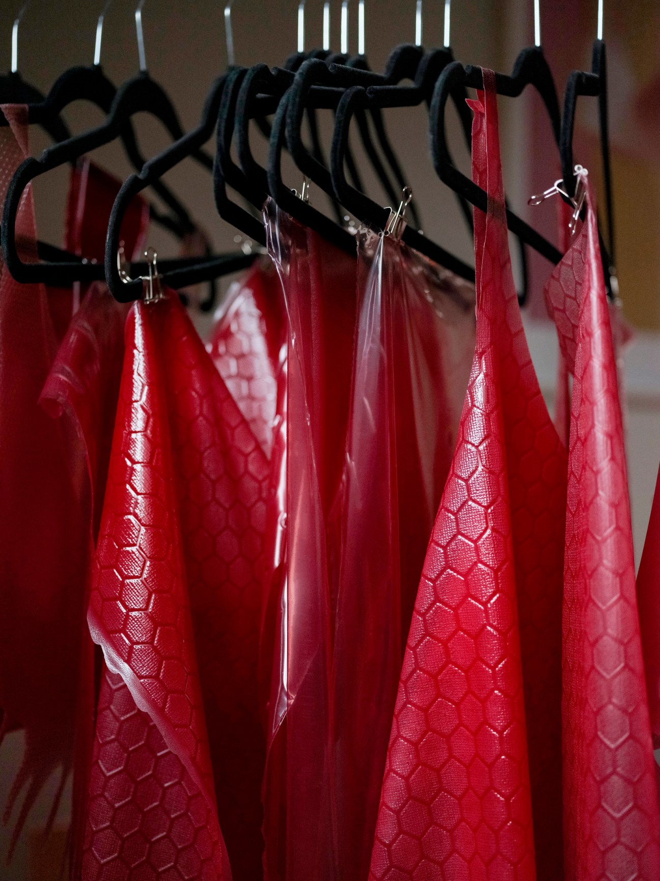 Red leather-textured fabric samples hanging on black hangers