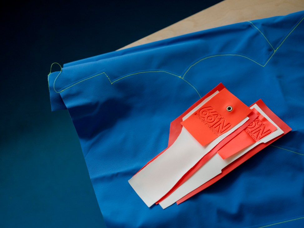 Close-up detail of 66°North jacket showing red and white labels, blue fabric with green stitching lines
