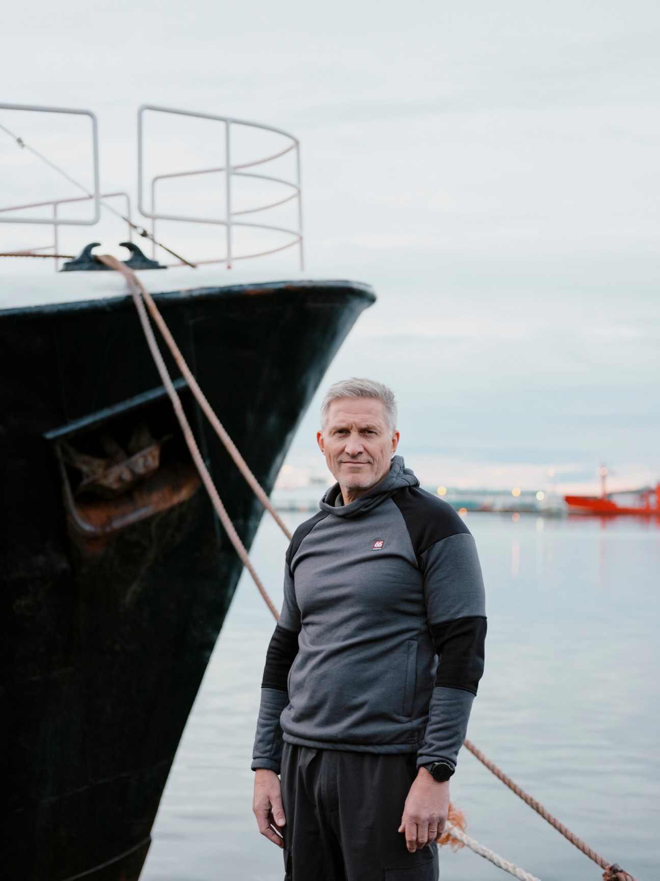 Helgi Oskarsson, CEO of 66°North, standing beside a boat at a harbor wearing dark outerwear