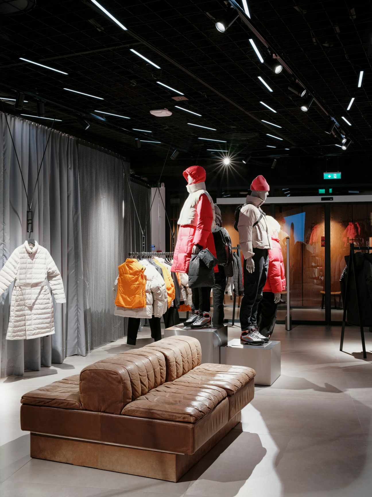 Interior of 66°North flagship store in Reykjavík with brown leather seating, mannequins in winter jackets, and modern retail design