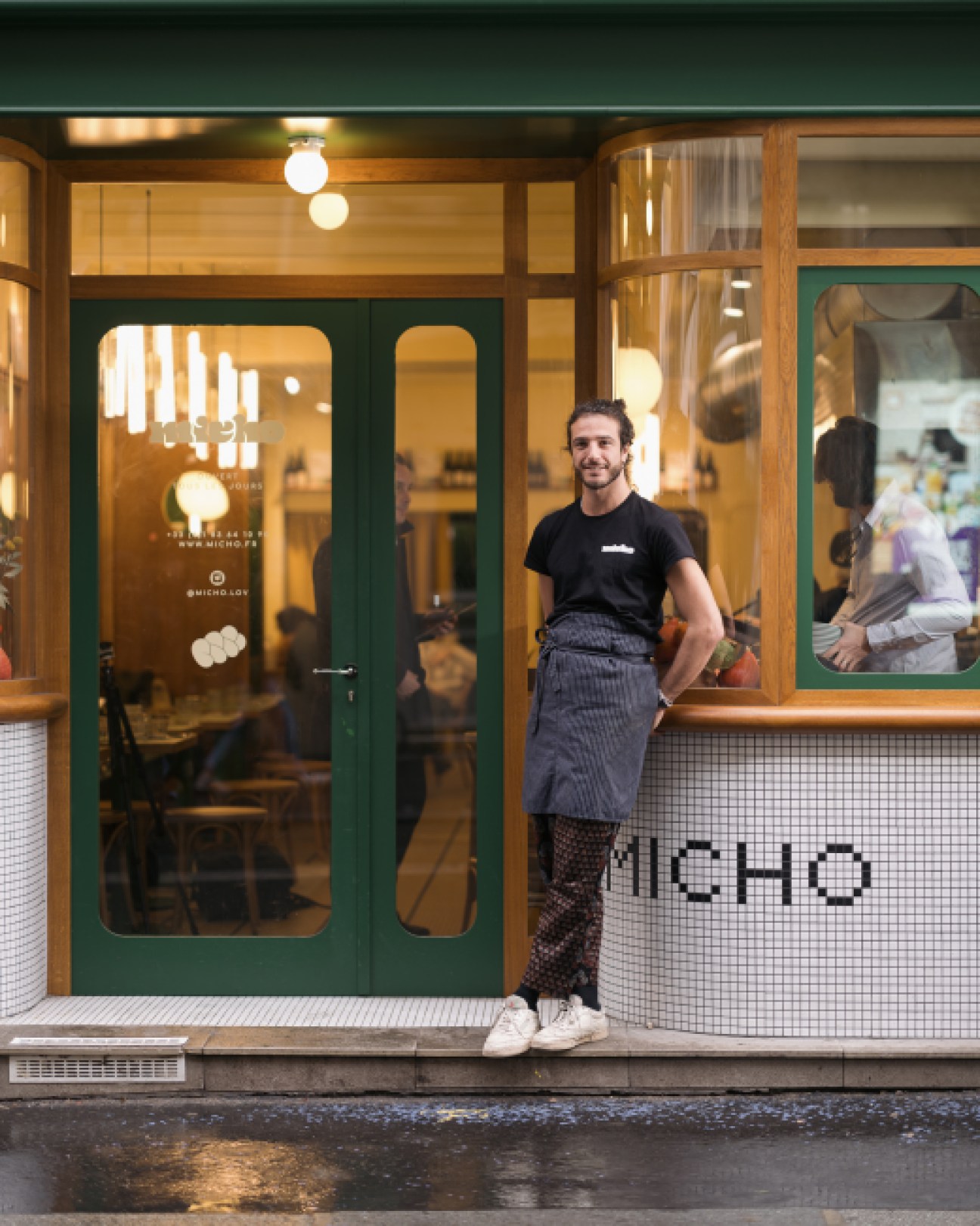 Chef Julien Sebbag standing outside Micho restaurant in Paris with green and white tiled facade