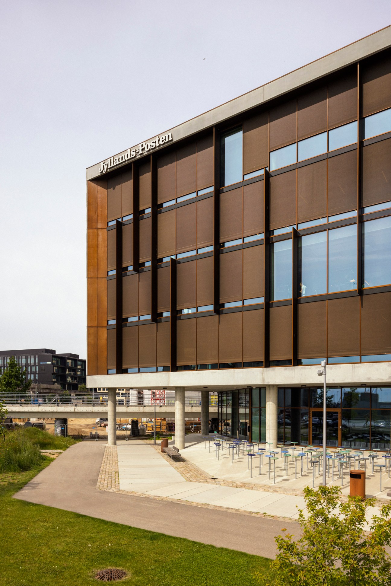 Modern glass and bronze facade of Jyllands-Posten newspaper headquarters building with geometric window panels