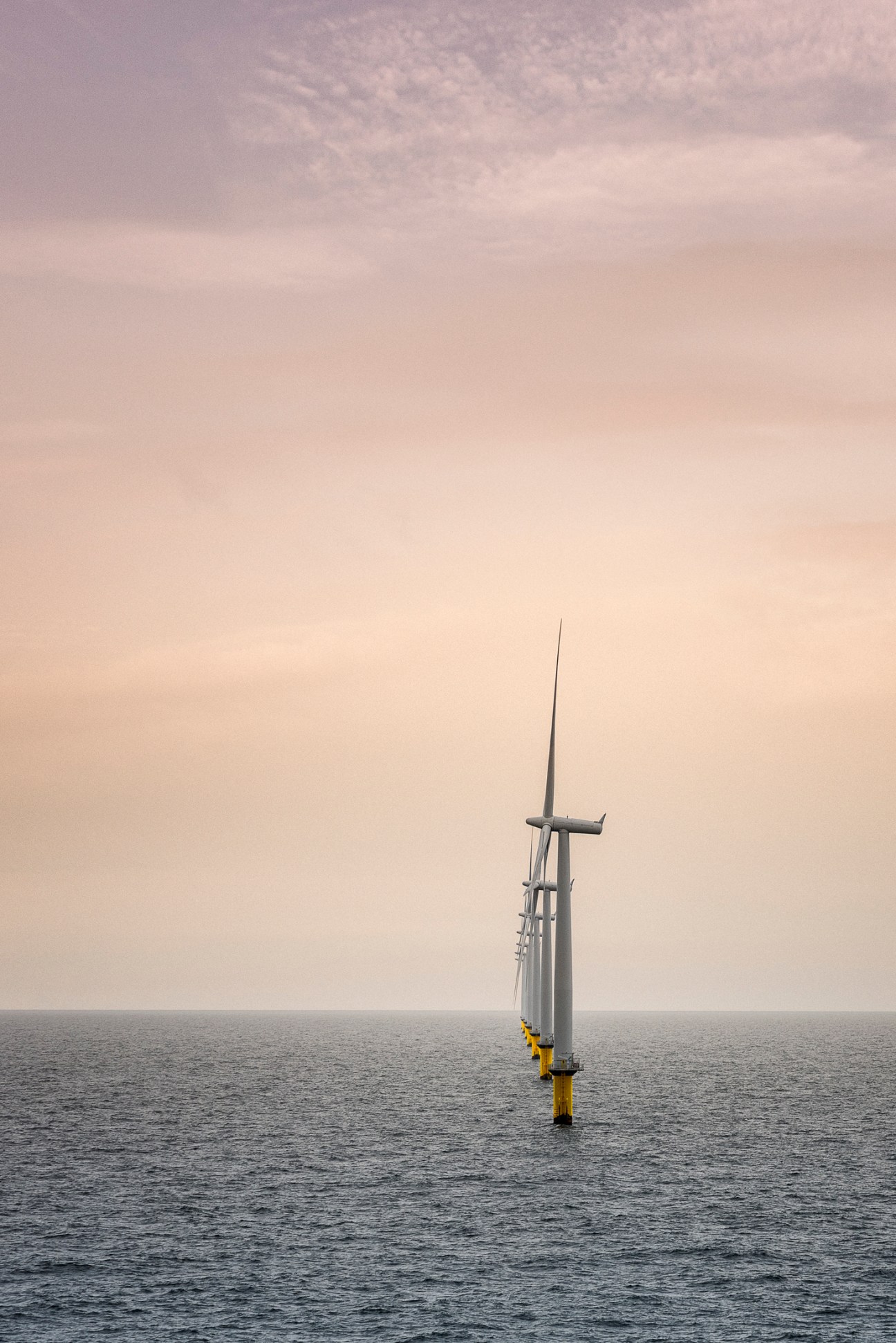 Single offshore wind turbine standing in choppy seas under overcast sky