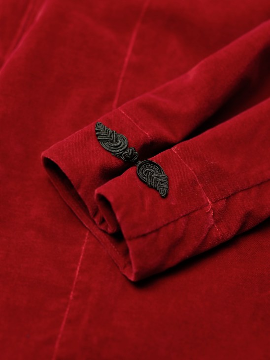 Close-up of red fabric cuff with decorative black embroidered leaf pattern detail