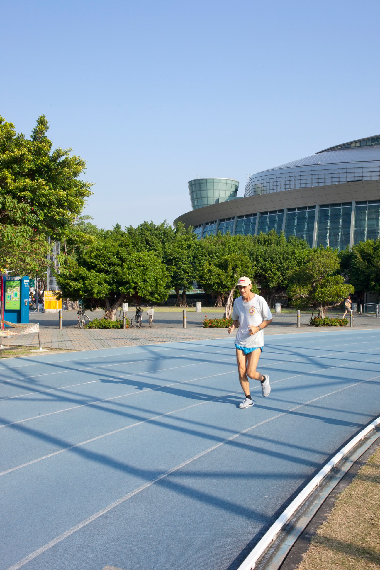 Person jogging on blue tiled plaza with modern glass building in background