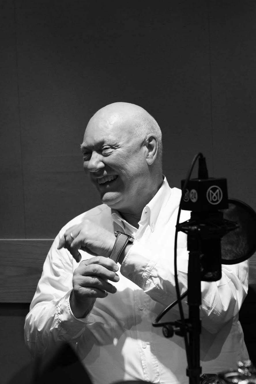 Jean-Claude Biver smiling while holding a piece of film strip in a black and white photograph