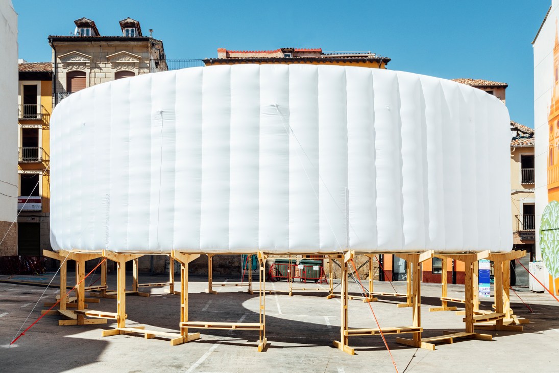 Large white inflatable dome structure with wooden support frame in a historic plaza surrounded by traditional European buildings.