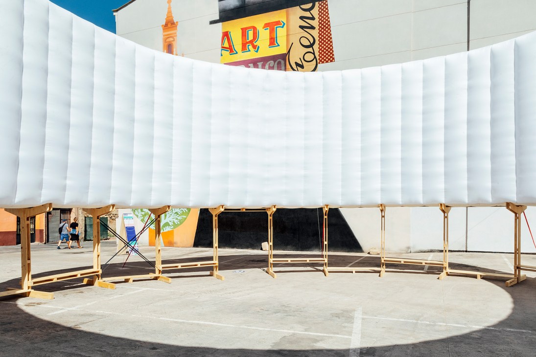 White fabric banners hanging from wooden frames creating temporary outdoor stalls