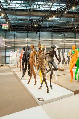 Colorful display of mannequins in various poses at a retail design fair.