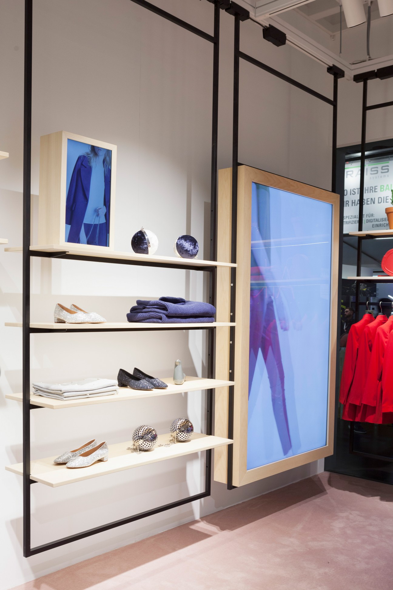 Modern retail display shelving with clothing, shoes, accessories and digital screens in The Village at EuroShop.