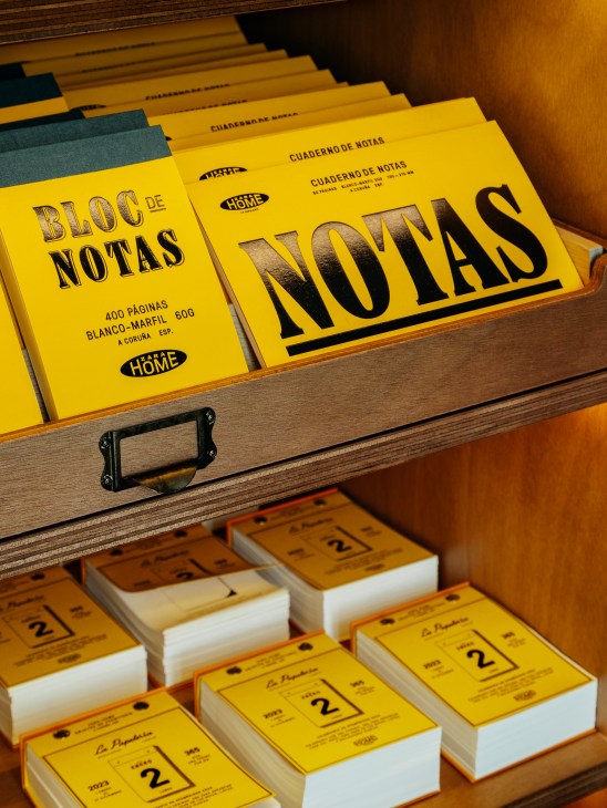 Yellow notebooks and calendars with Spanish text displayed in wooden drawer compartments