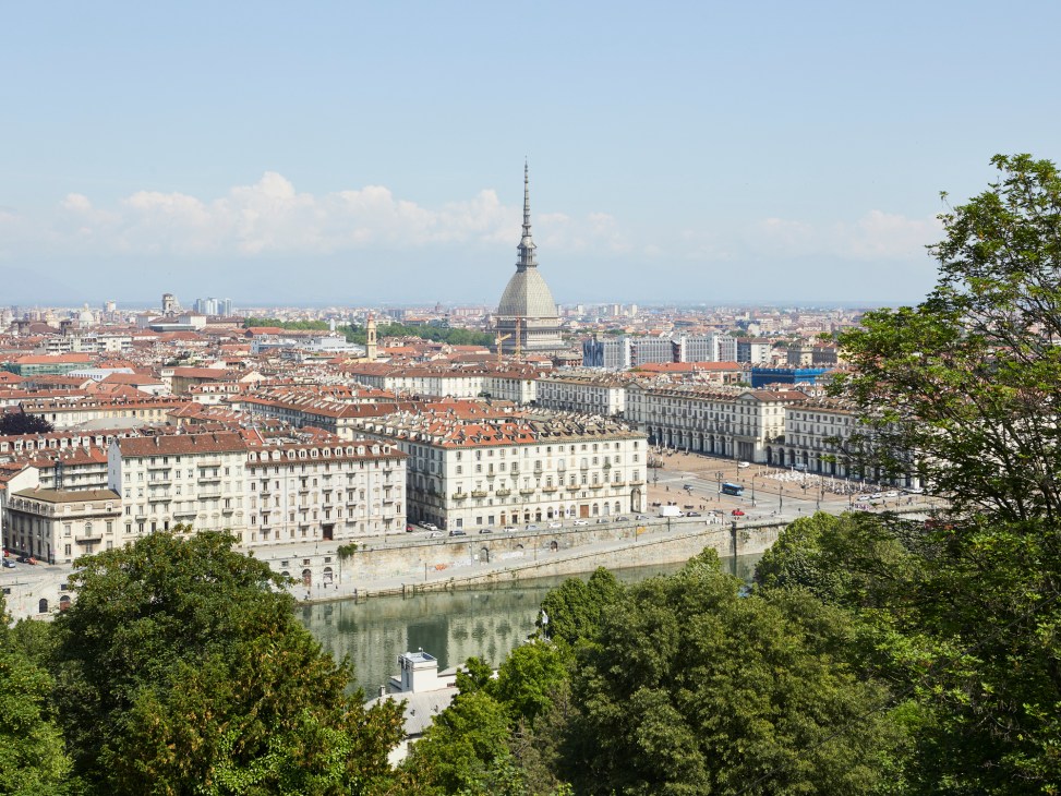 Elevated view of Turin's downtown skyline with the Mole Antonelliana dome, river, and surrounding cityscape.