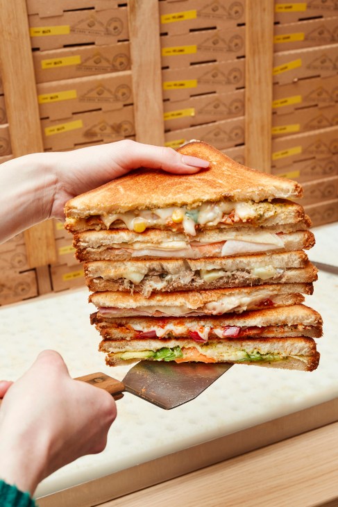 Six different croque monsieur sandwiches stacked and displayed showing variety of fillings