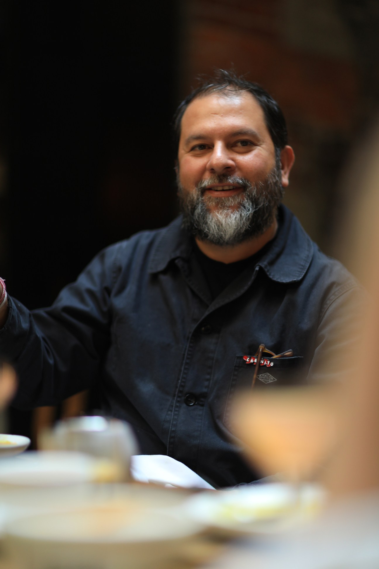 Enrique Olvera smiling at camera wearing dark shirt in restaurant setting
