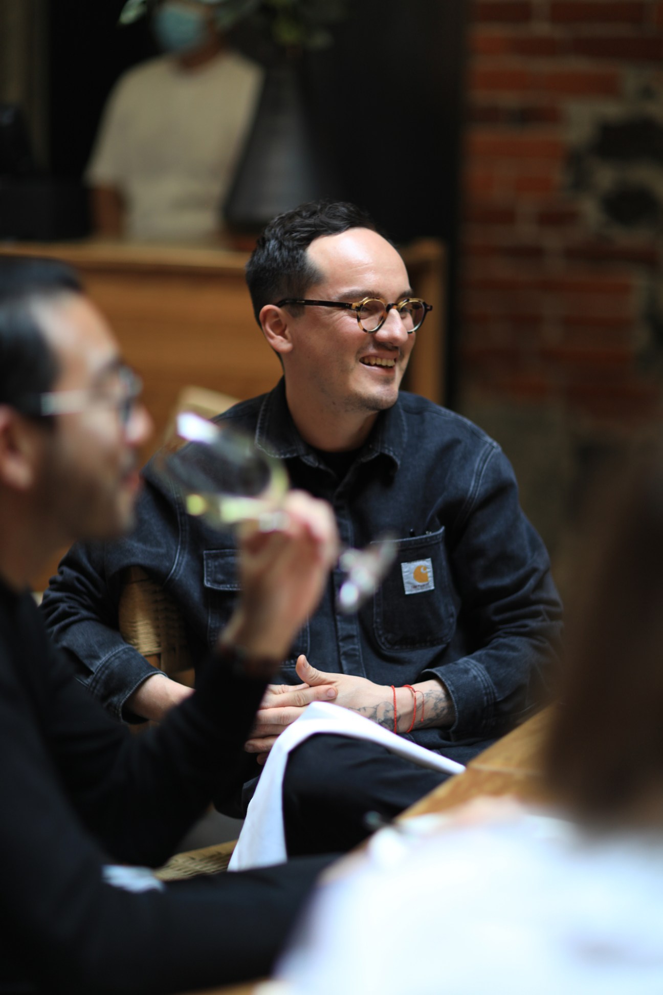 Smiling man in glasses and dark shirt sitting at restaurant table during discussion