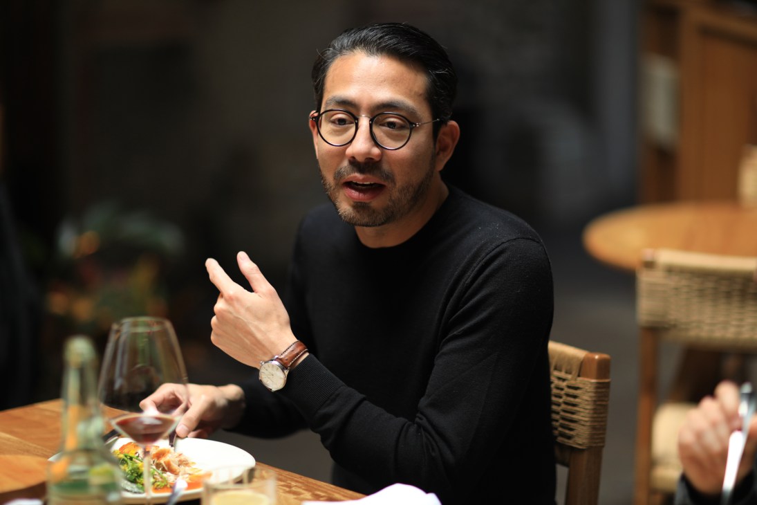 Edo Kobayashi gesturing while speaking at a restaurant table with food and drinks