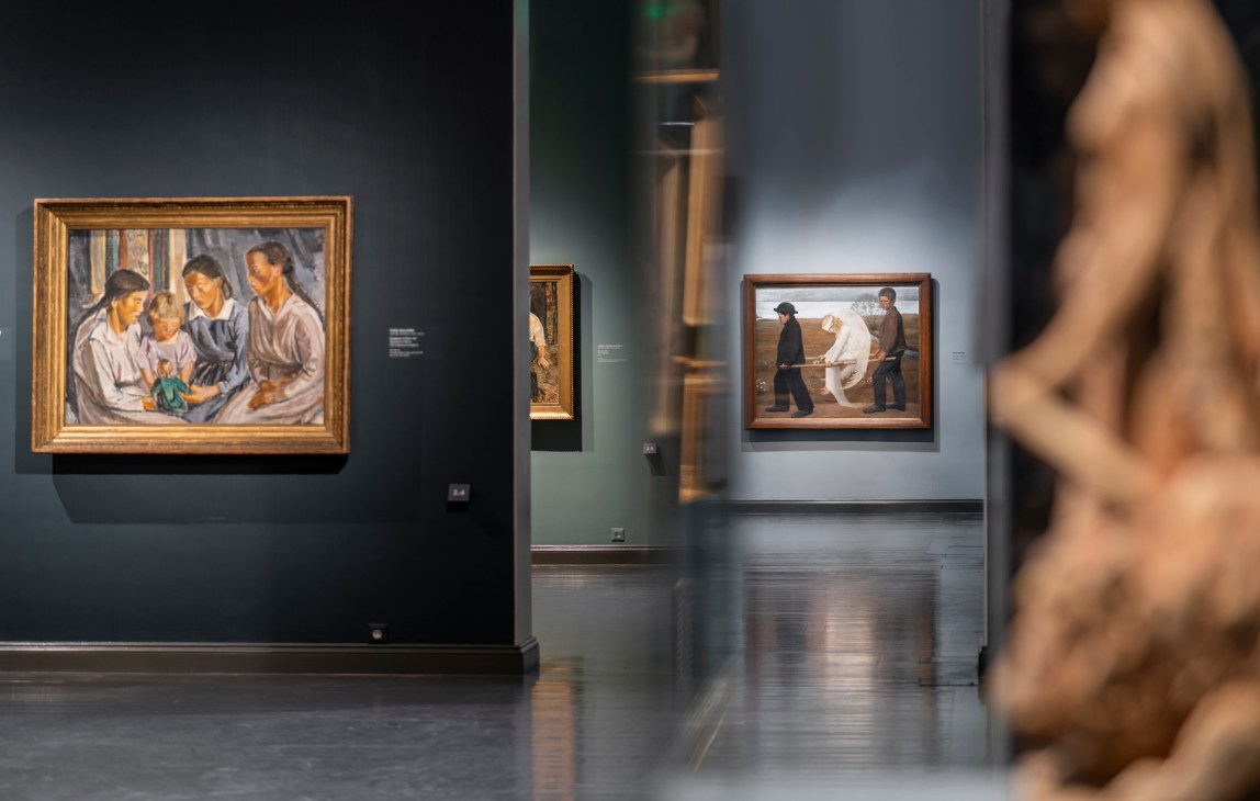 Visitors viewing artwork in a gallery space with paintings on white walls