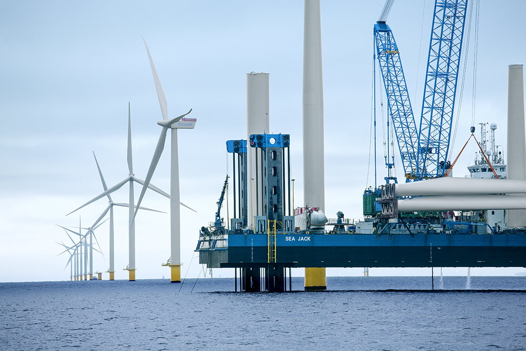 Large offshore wind turbines being constructed at sea with installation vessel and crane equipment visible