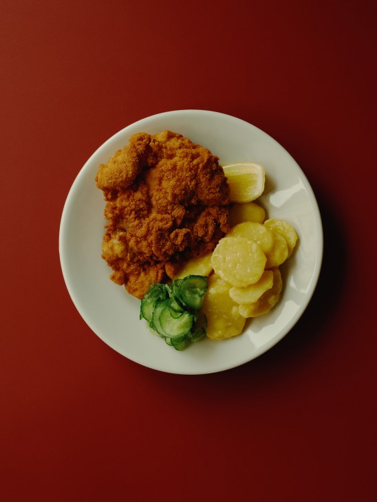 Austrian fried chicken served with pickled vegetables and lime wedge on white plate
