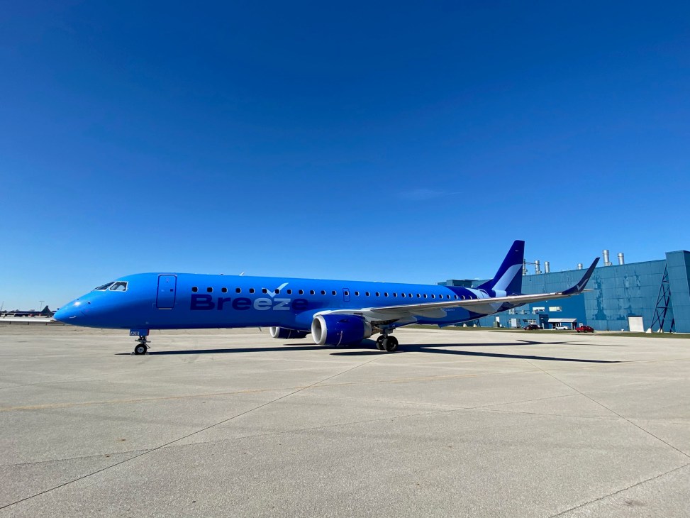 Breeze Airways blue aircraft parked on airport tarmac under clear sky