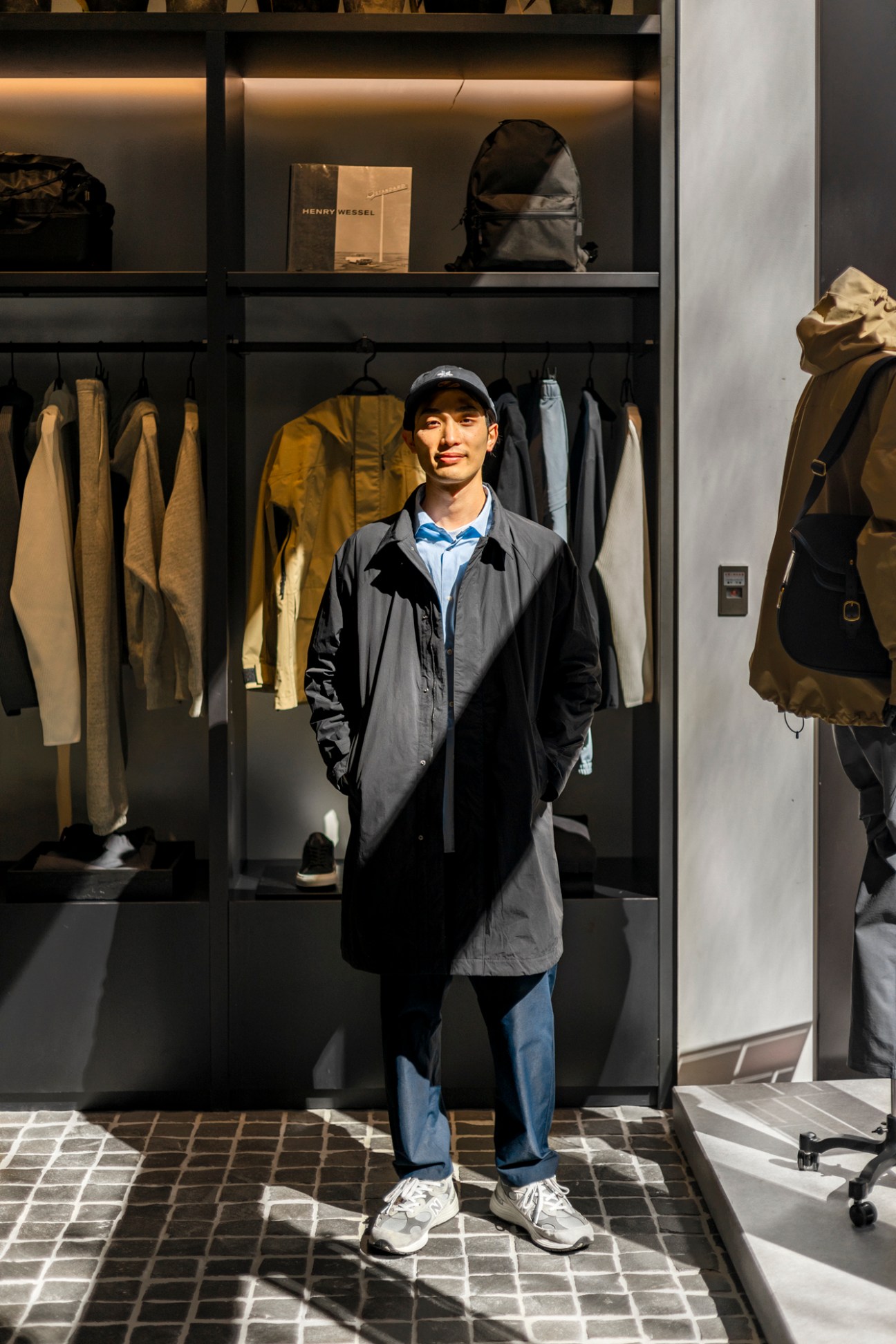 Yuta Saito, assistant at Goldwin Marunouchi shop, standing in modern minimalist retail store wearing dark technical coat