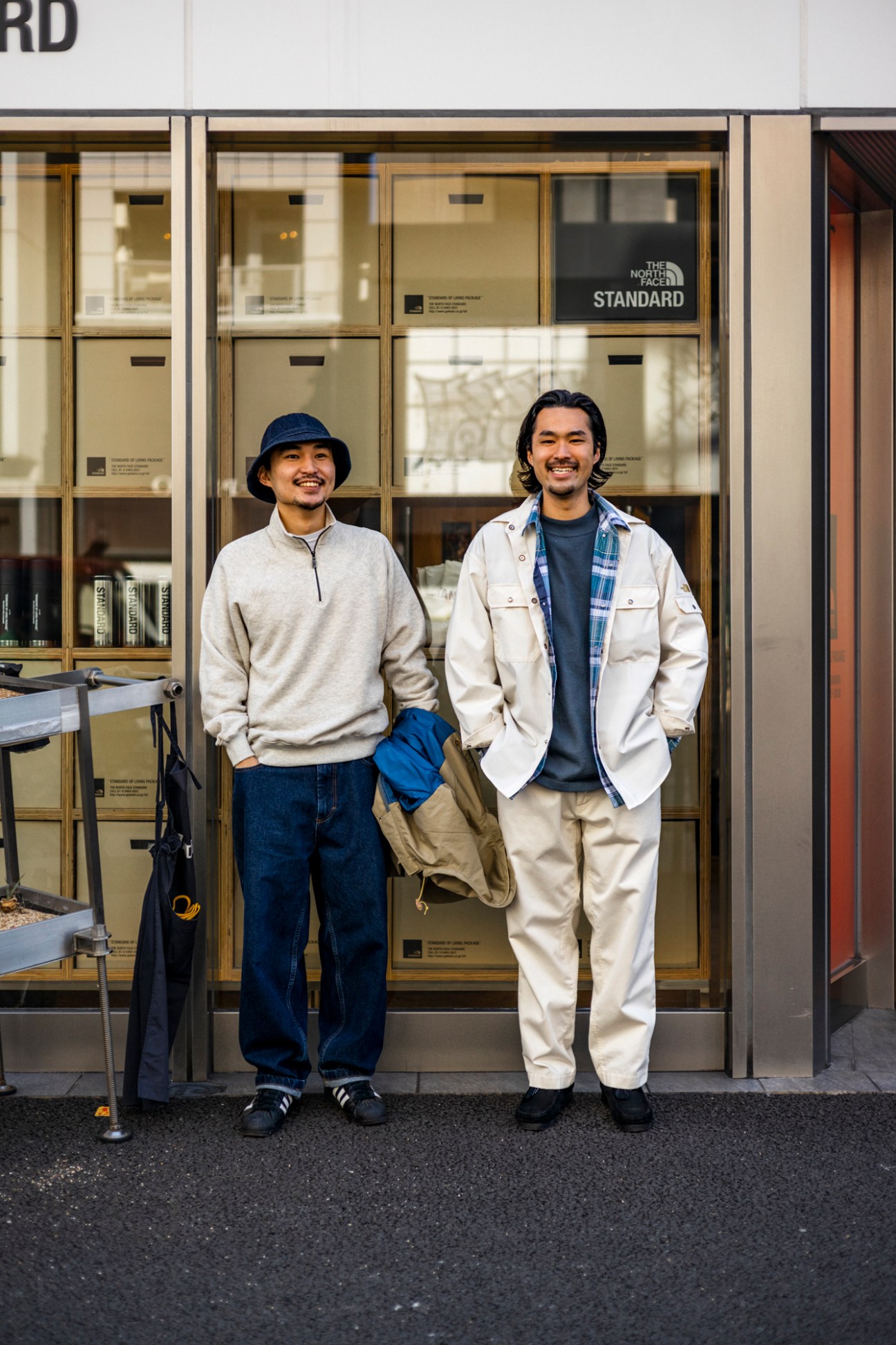 Two smiling Japanese men in casual outdoor wear standing outside The North Face Standard shop in Harajuku