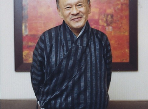 Man standing in dark blue stripy clothes smiling at camera