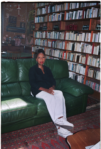 Woman sitting on green leather sofa in front of bookshelf